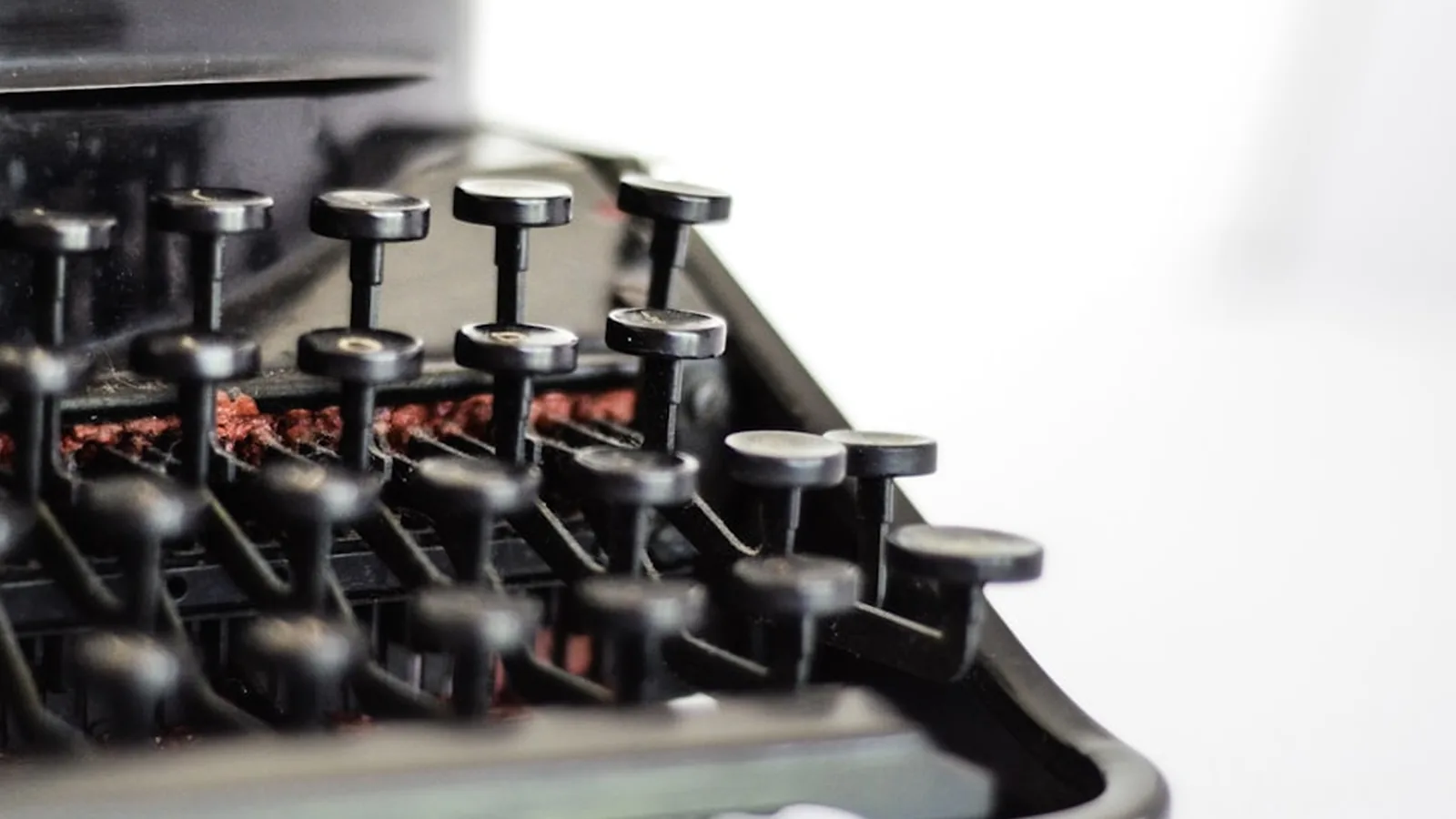 Close-up of the black typebars and round keys of an antique typewriter against a white background
